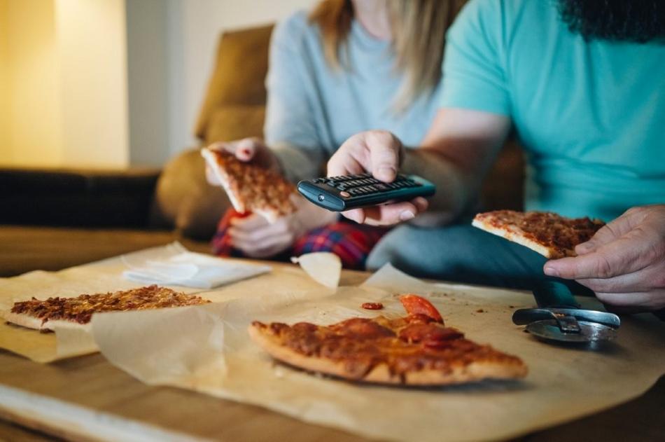 Paar isst Pizza beim Fernsehgucken