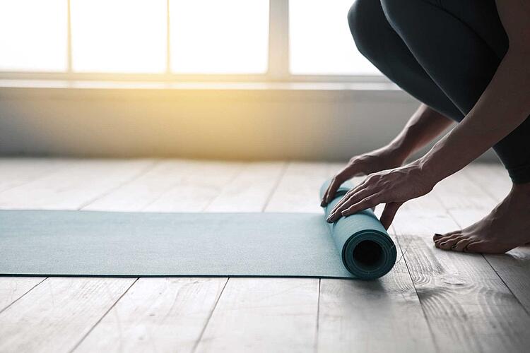 Frau rollt eine Yogamatte aus