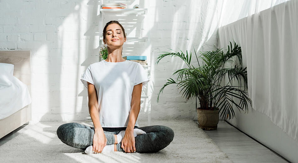 Frau macht Yoga im Schlafzimmer.