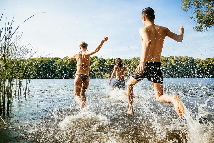 Junge Leute laufen in einen Badesee