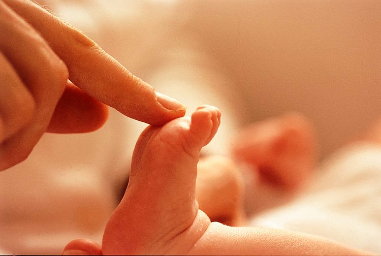 Bildnachweis: © wdv / Jan Lauer Frau tippt mit dem Finger auf den Fuß eines Babys.