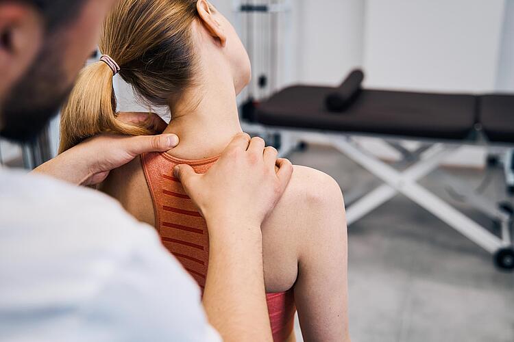 Physiotherapeutin massiert schmerzende Nacken einer Frau