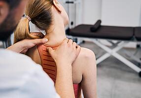 Physiotherapeutin massiert schmerzende Nacken einer Frau