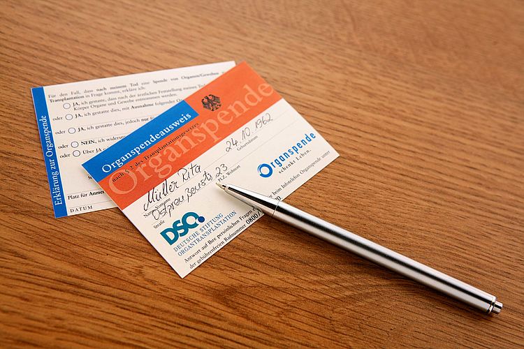 Bildnachweis: © wdv / Oana Szekely Organspendeausweis Vorder- und Rückseite und ein Kugelschreiber liegen auf einem Holztisch