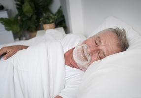 Älterer Mann liegt im Bett und schläft