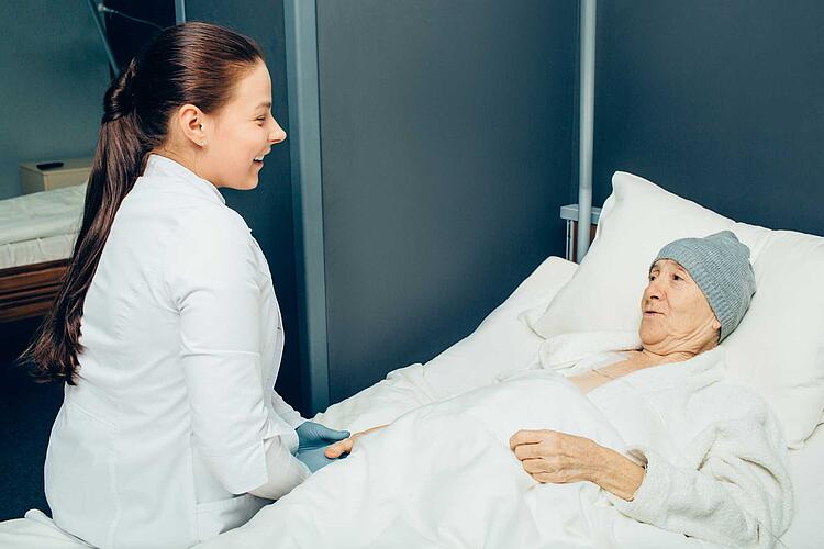 Ärztin sitzt bei Patientin am Bett