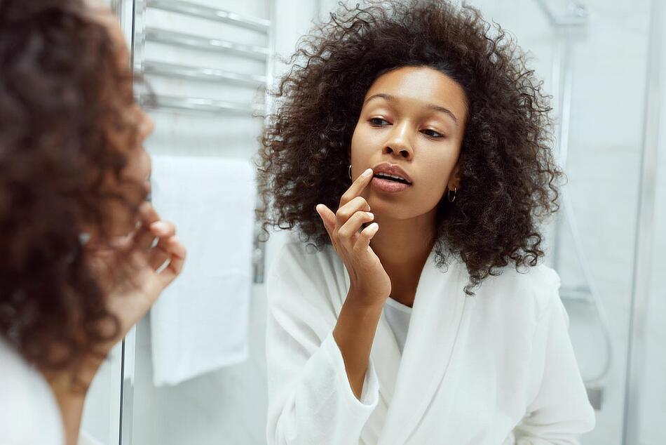 Frau cremt sich die Lippen ein - Bildnachweis: © istockphoto.com / istockphoto.com Frau cremt sich die Lippen ein