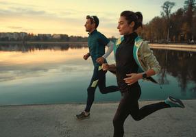 Junge Frau und junger Mann joggen bei Sonnenaufgang