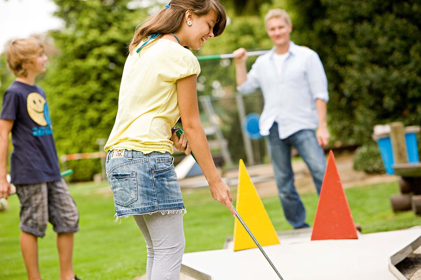 Familie spielt Minigolf.