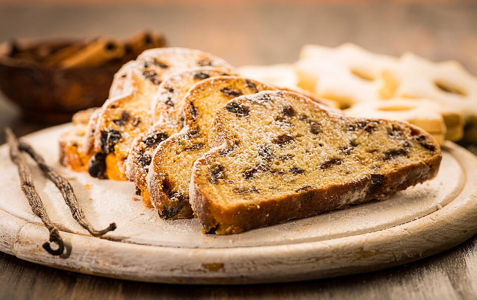 Christstollen mit Vanillestangen auf einem Holzbrett.