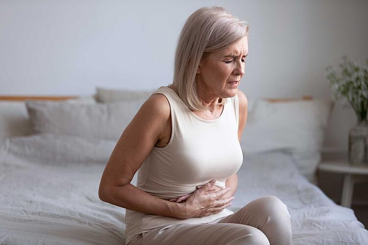 Magenschleimhautentzündung – Frau presst ihre Hände auf den schmerzenden Bauch