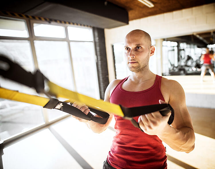 Mann beim Sling-Training im Studio.