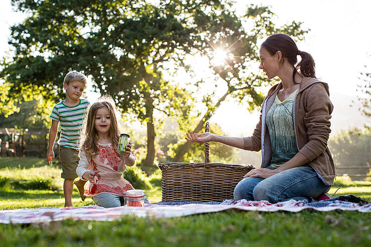 Mutter mit ihren Kindern beim Picknick im Park.