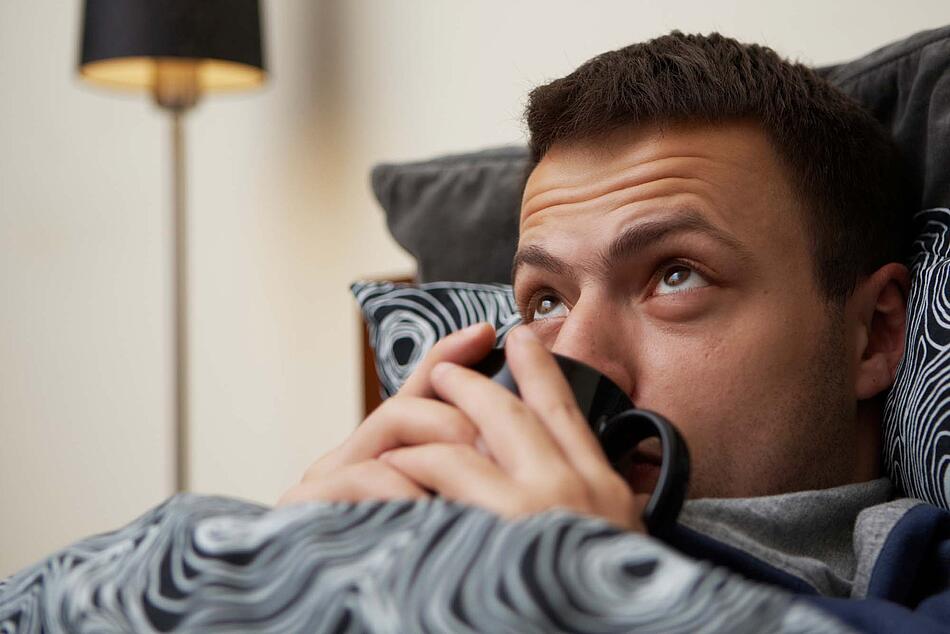 Ein Mann liegt im Bett und trinkt Tee. - Bildnachweis: © istockphoto.com / Chalabala Ein Mann liegt im Bett und trinkt Tee.