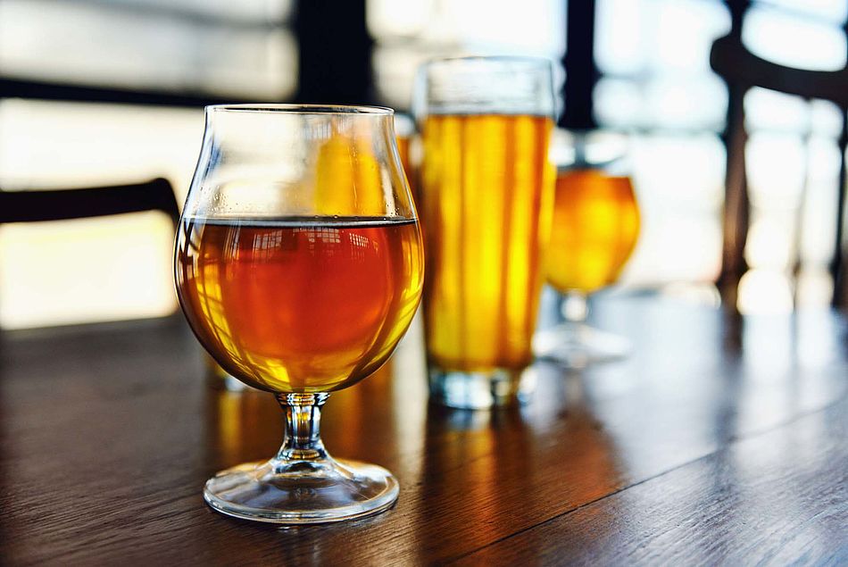 Verschiedene Gläser mit Bier stehen auf einem Holztisch. – Bild: stocksy.com © Daxiao Productions - Bildnachweis: © stocksy.com / Daxiao Productions Verschiedene Gläser mit Bier stehen auf einem Holztisch.
