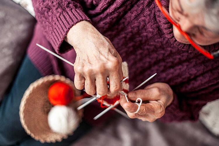 Frau mit Rheuma in den Händen strickt.