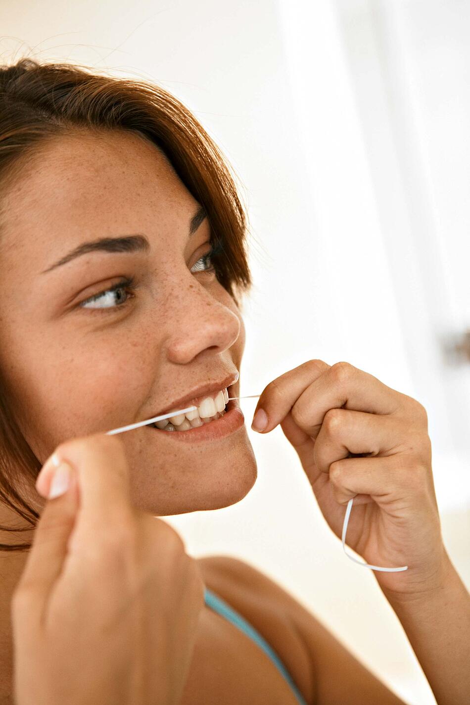 Frau benutzt Zahnseide.
