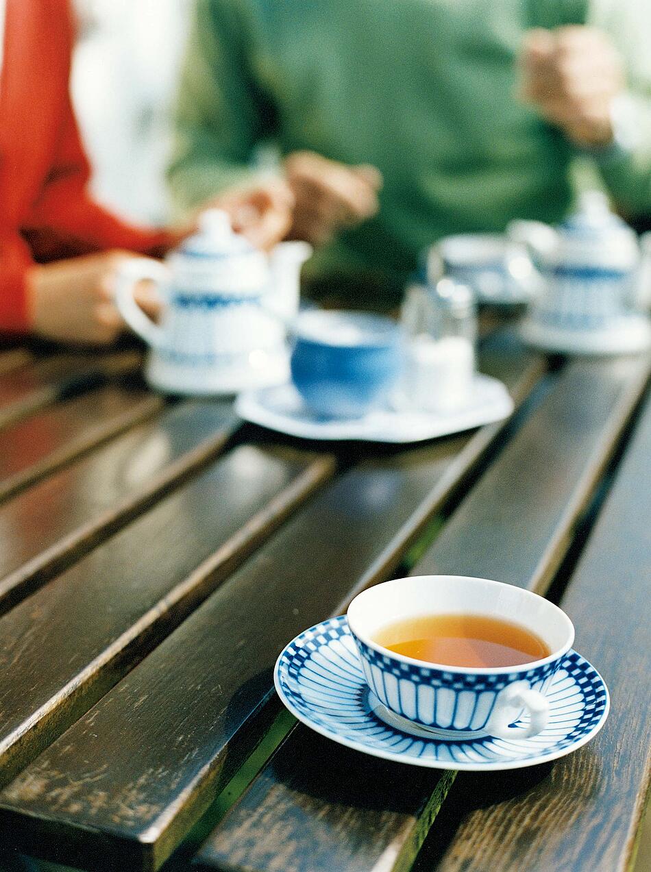 Eine gefüllte Teetasse aus Porzellan auf einem Holztisch.