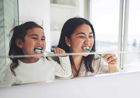 Mutter und Tochter putzen gemeinsam ihre Zähne