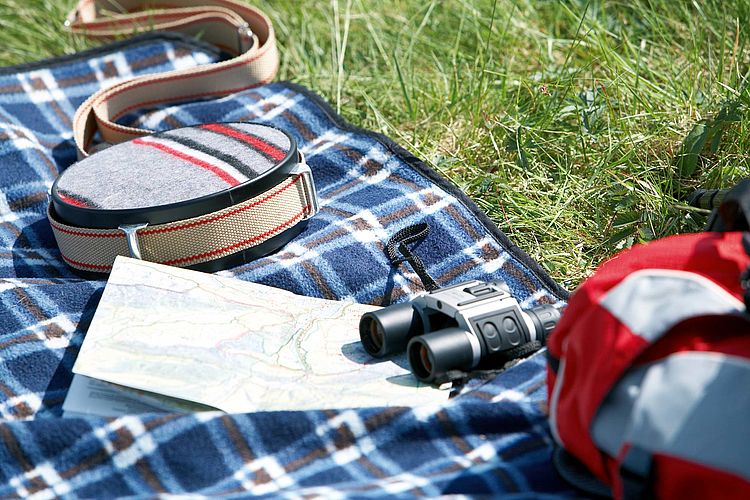 Bildnachweis: © wdv / Oana Szekely Fernglas, Wanderkarte und Feldflasche auf einer Campingdecke.