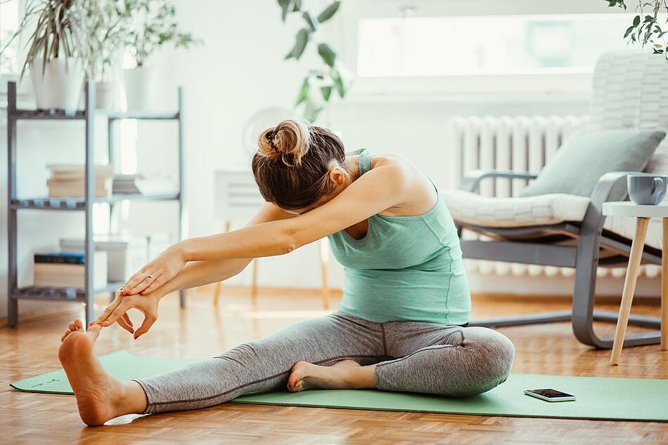 Schwangere macht Yoga im Wohnzimmer