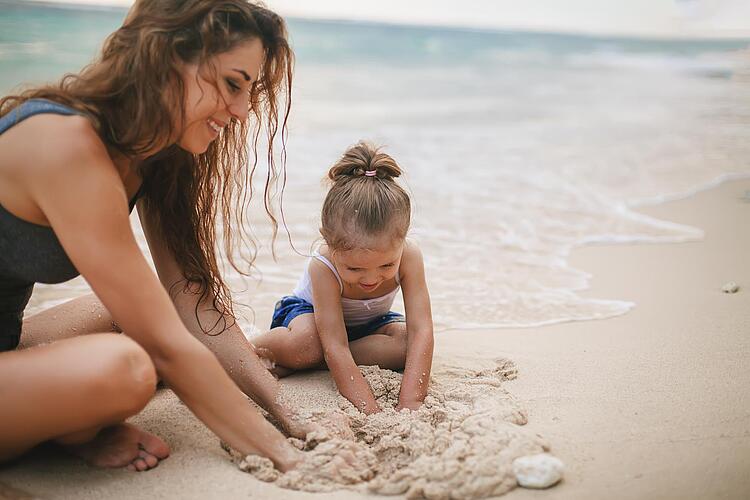 Mutter und Tochter spielen am Strand