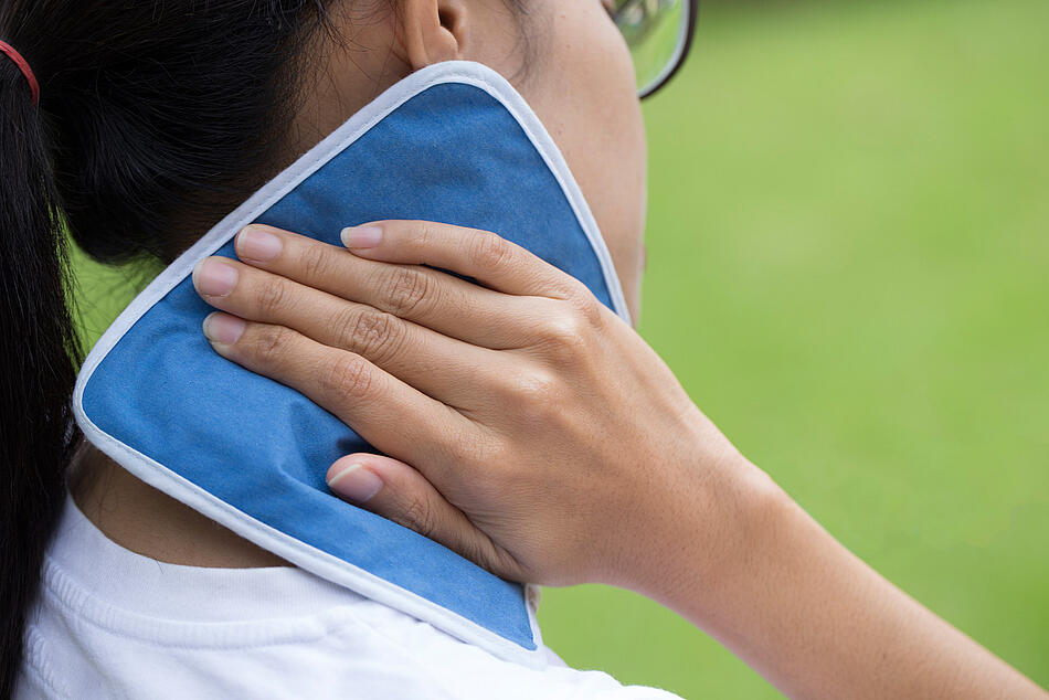 Eine Frau kühlt ihren Nacken mit einem Kühlkissen. - Bildnachweis: © istockphoto.com / Tatomm Eine Frau kühlt ihren Nacken mit einem Kühlkissen.