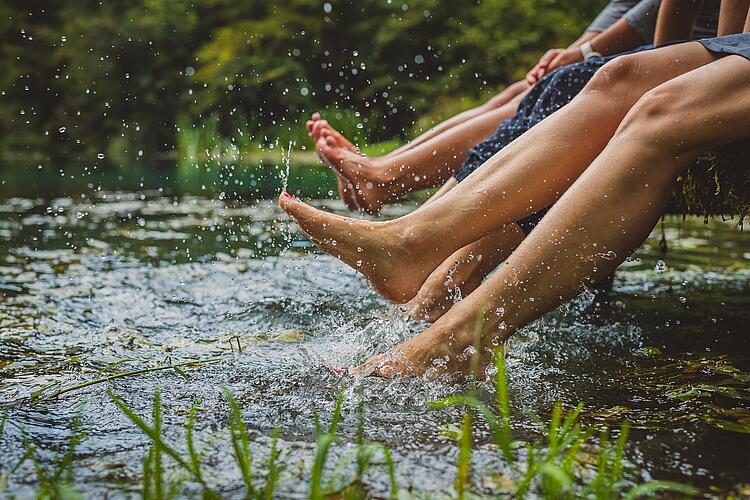 Füße baumeln vom Steg ins Wasser