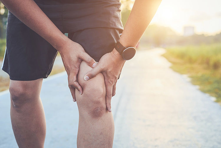 Bildnachweis: © stock.adobe.com / phanuwatnandee Ein Jogger fasst sich an sein Knie.