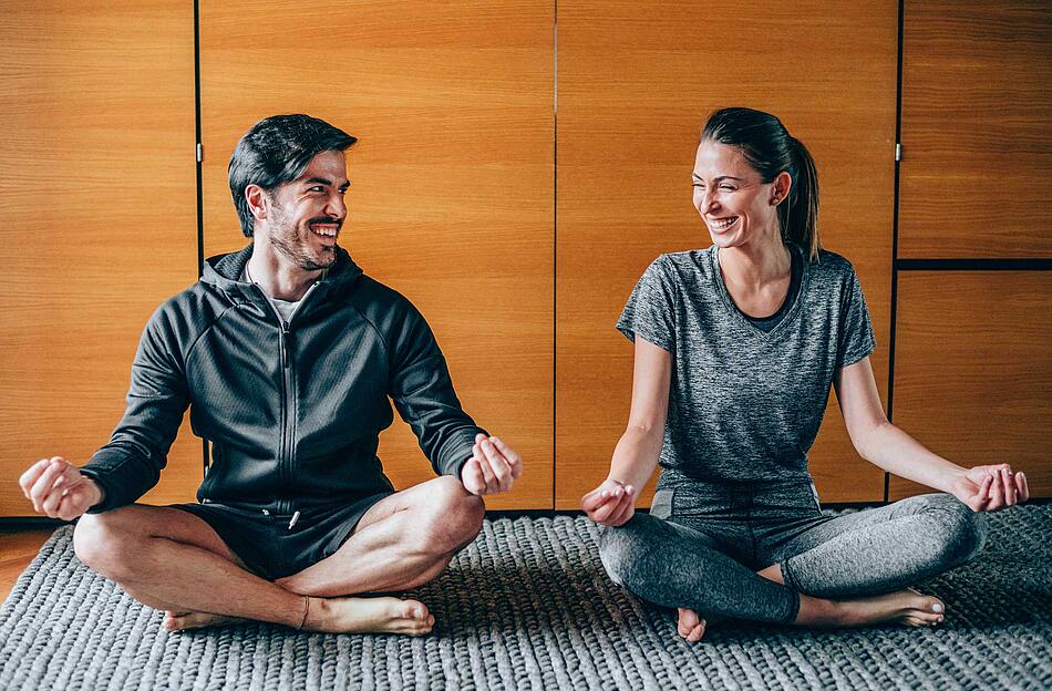 Mann und Frau lachen beim Yoga