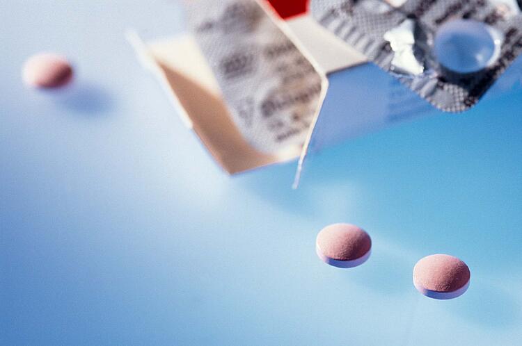 Eine Medikamentenschachtel und einige einzelne Tabletten.