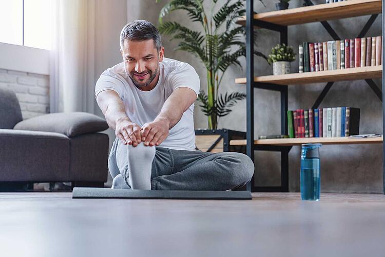 Mann macht Yoga im Wohnzimmer