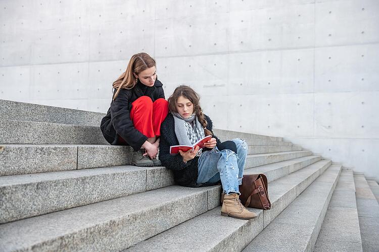 Zwei junge Frauen sitzen auf einer Treppe