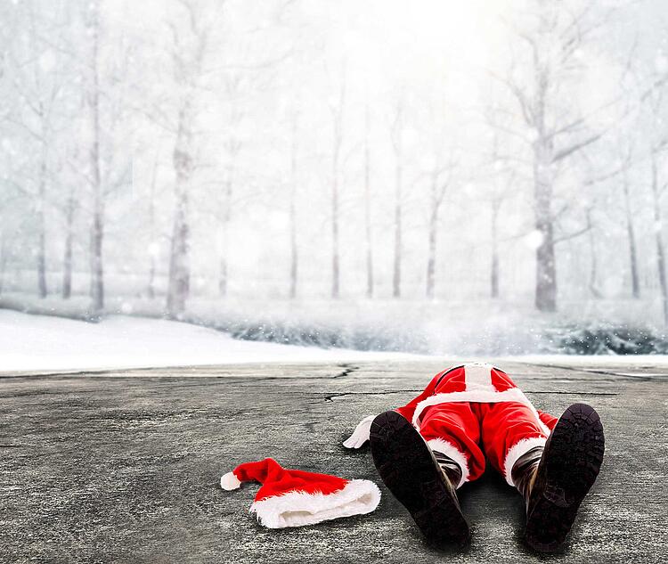 Weihnachtsmann liegt auf dem Rücken auf einer winterlichen Straße