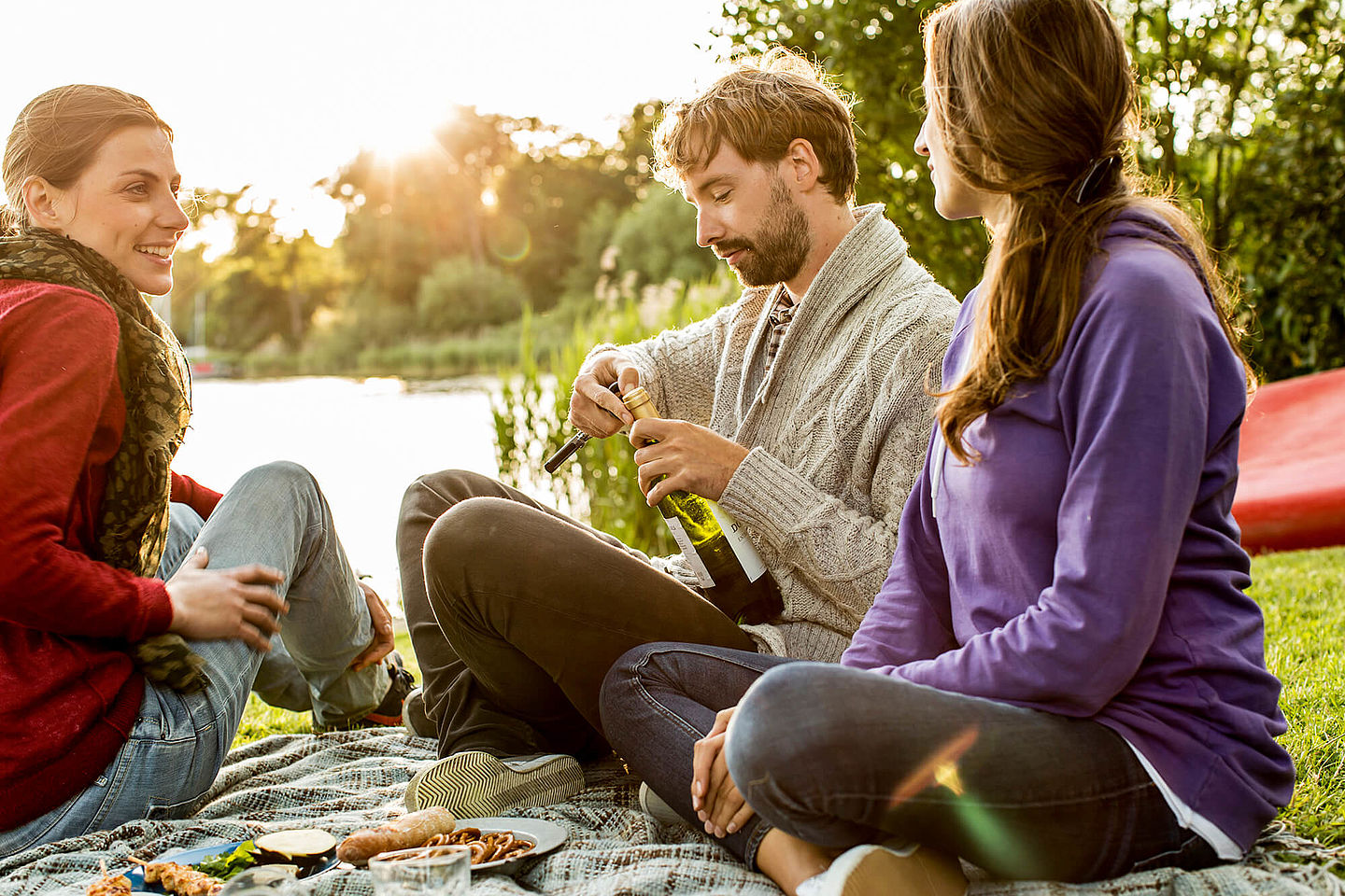 Jugne Leute beim Picknick an einem Seeufer.
