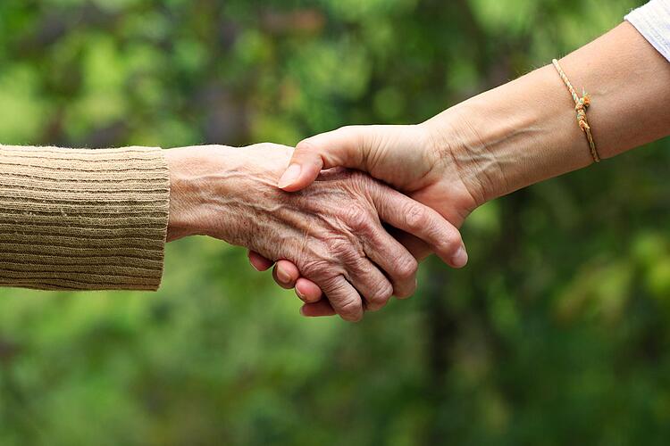 Hand einer jungen Frau hält die Hand einer älteren Frau