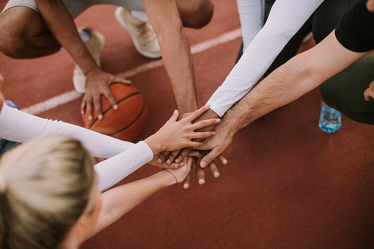 Basketballteam legt vor dem Spiel die Hände aufeinander
