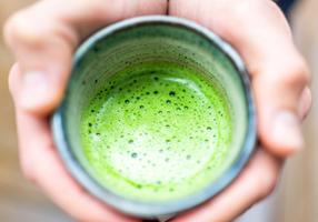 Mann hält einen Becher Matcha-Tee in beiden Händen