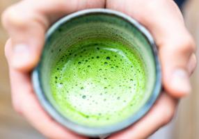 Mann hält einen Becher Matcha-Tee in beiden Händen