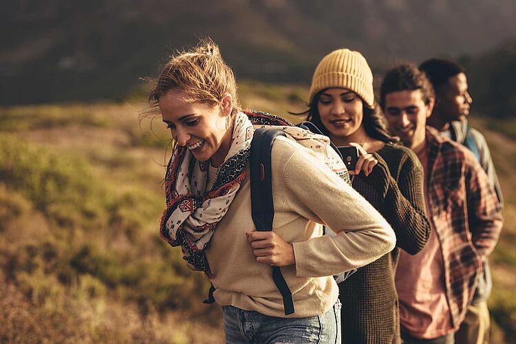 Junge Leute wandern über eine herbstliche Wiese