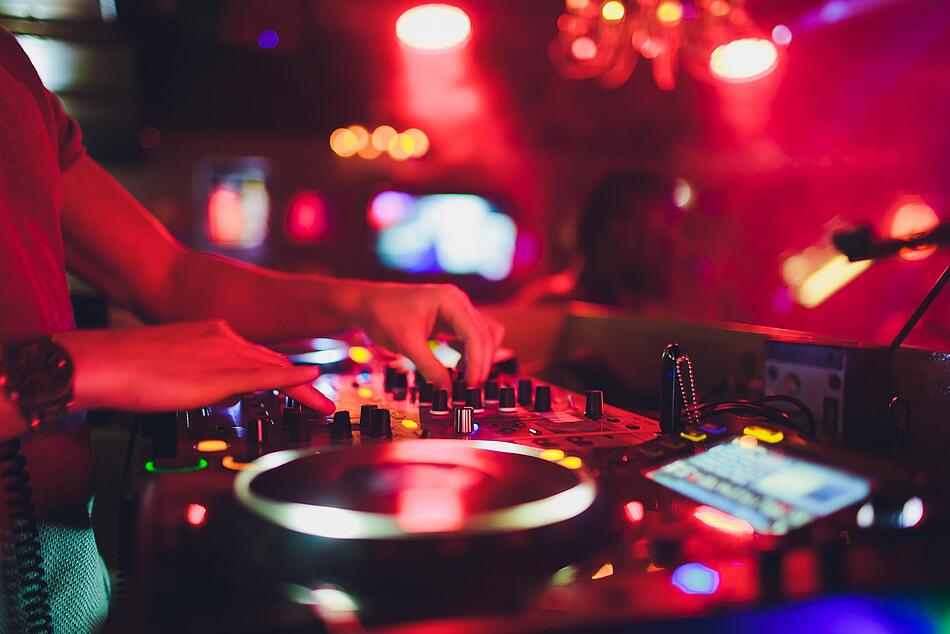 Hände eines DJ an einem Mischpult in einer Diskothek