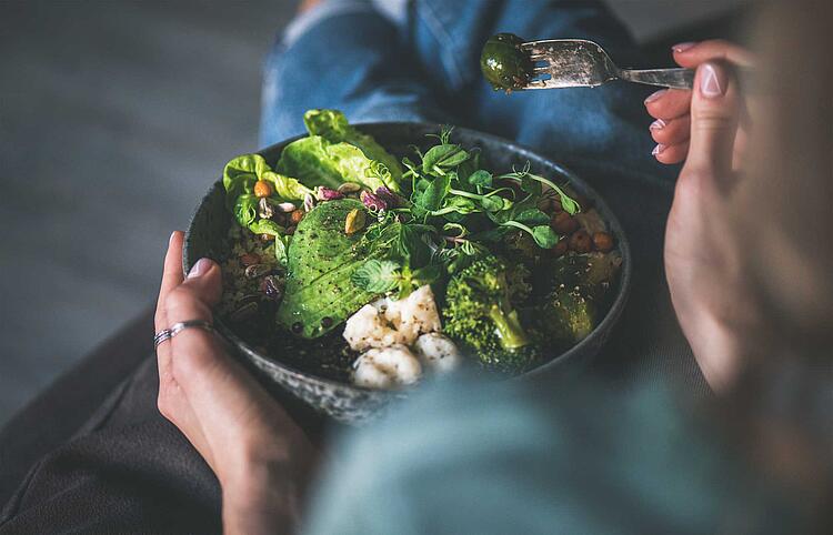 Frau isst eine Bowl mit Salat