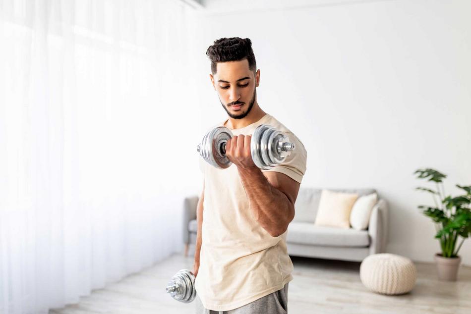 Junger Mann beim Hanteltraining zu Hause