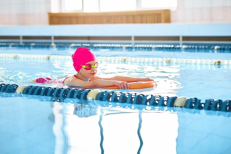 Schwimmen lernen: Kind mit Schwimmnudel im Wasser