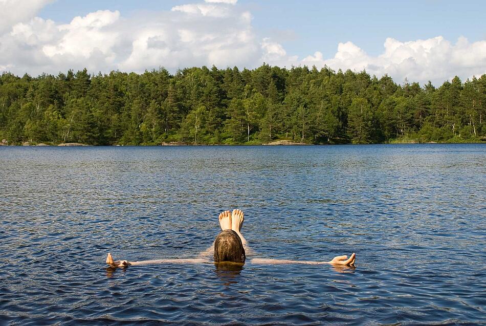 Mann lässt sich im See auf dem Rücken treiben