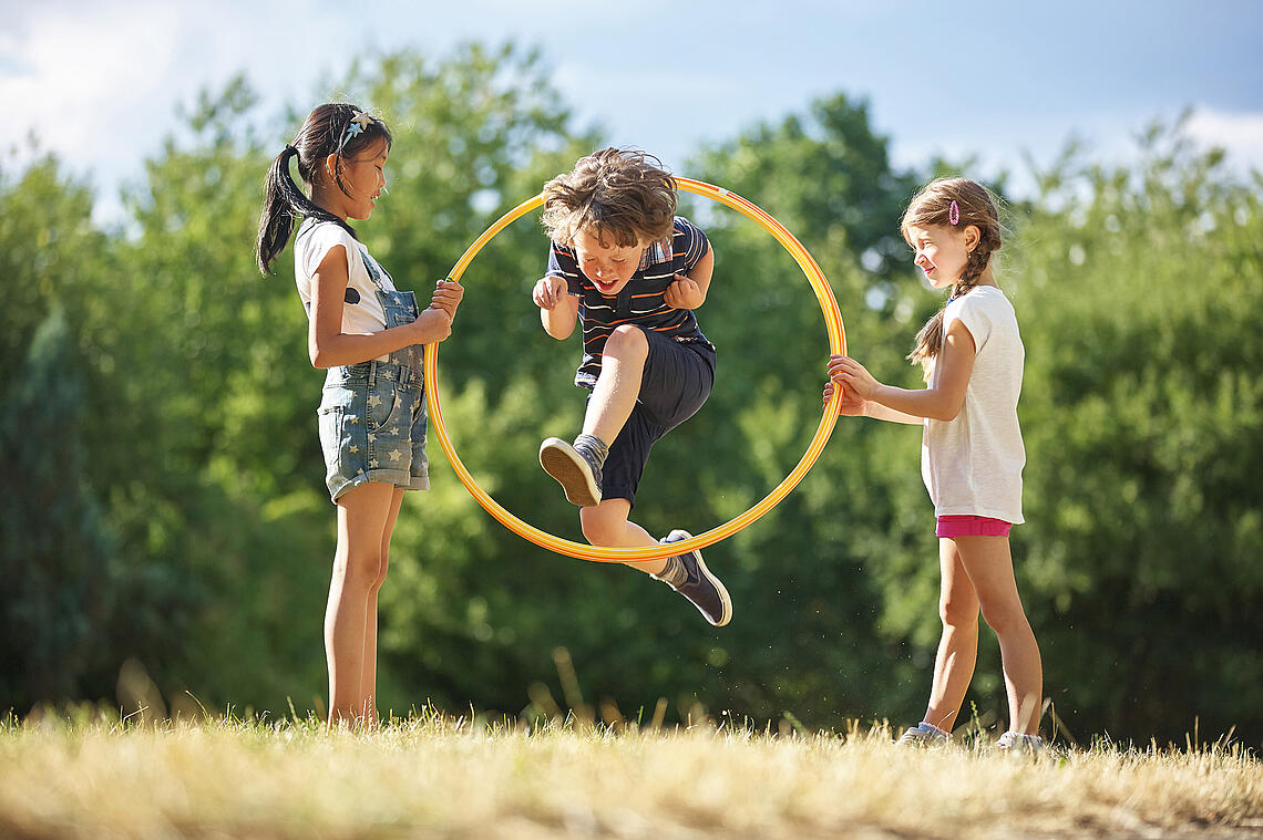 Junge springt durch einen Hula Hoop Reifen