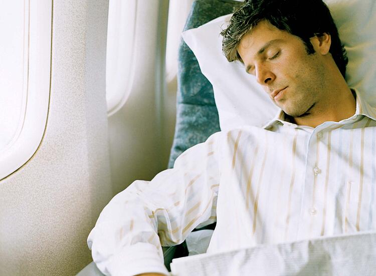 Mann schläft im Flugzeug.