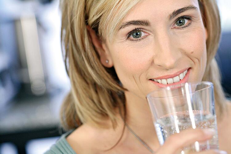 Eine Frau mit einem Glas Wasser in der Hand.