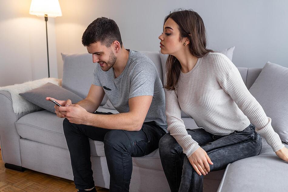 Frau versucht auf das Smartphone des Mannes zu schauen - Bildnachweis: © istockphoto.com / dragana991 Frau versucht auf das Smartphone des Mannes zu schauen