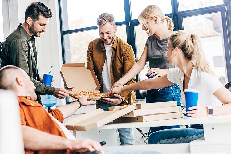 Kollegen essen gemeinsam Pizza im Büro